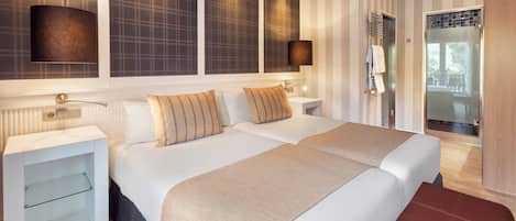Et moderne hotelværelse med to senge, en rød bænk, et glasbadeværelse og udsigt til det fri.
