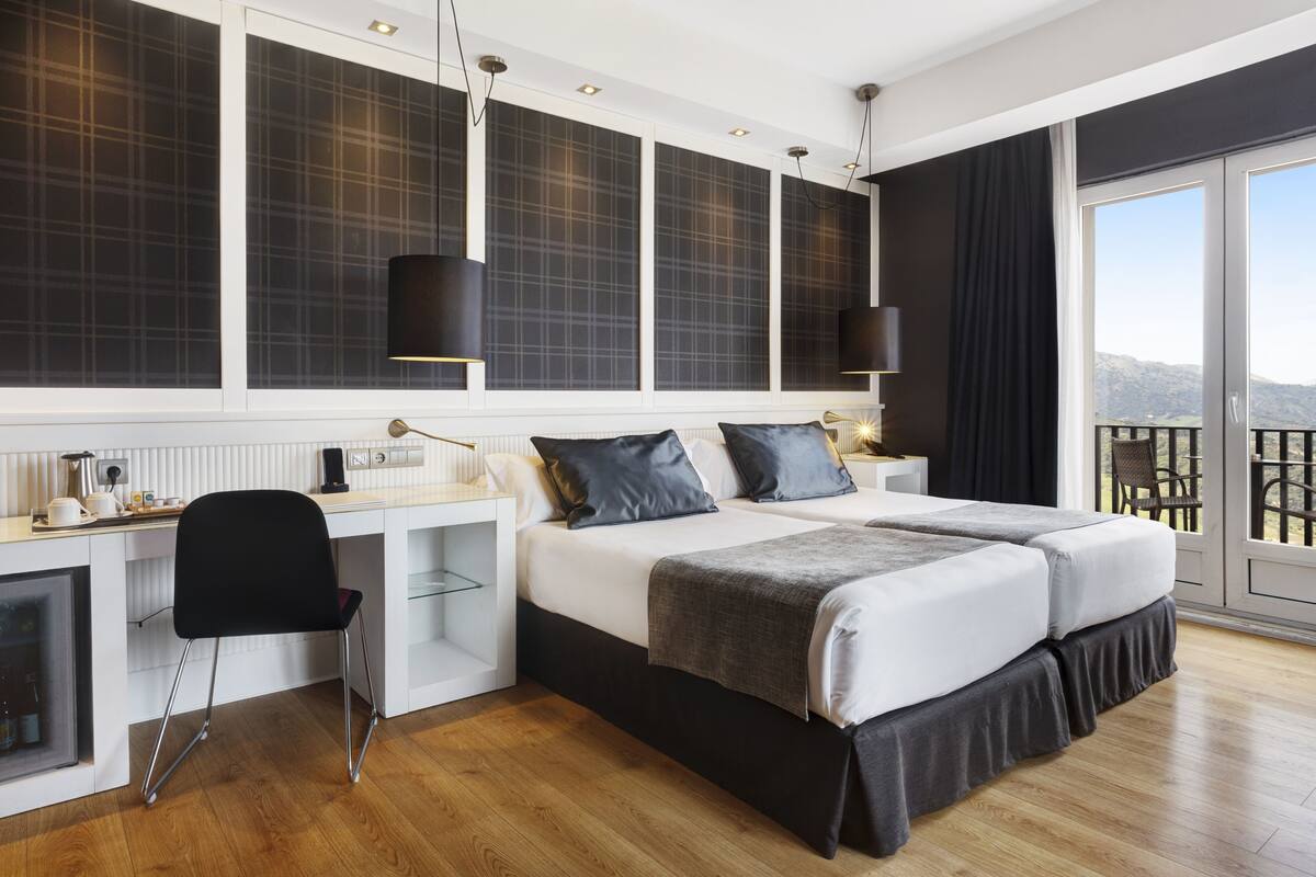 Ein modernes Schlafzimmer mit einem großen Bett, einem Schreibtisch und Blick ins Freie.