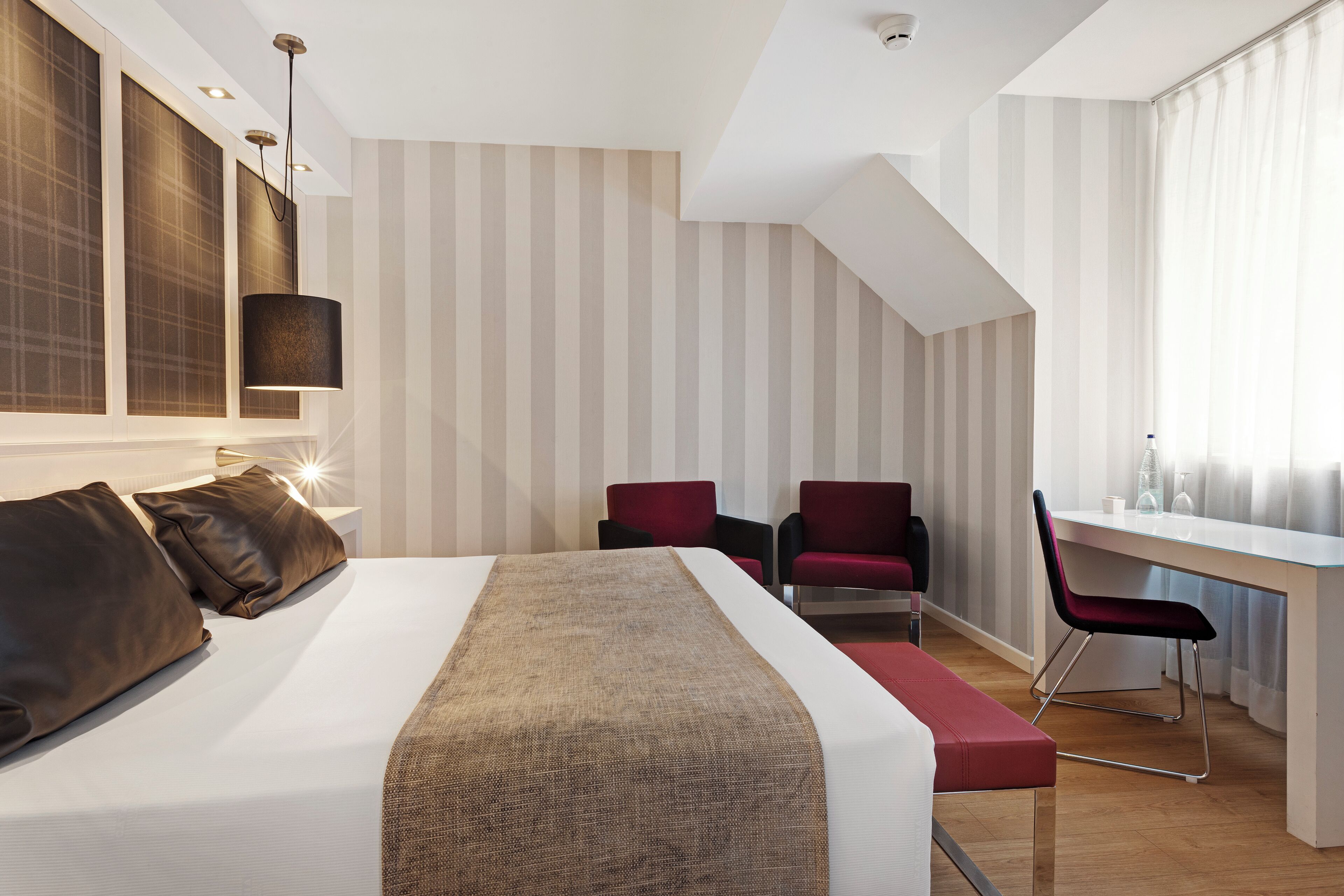 Una habitación de hotel moderna con una cama grande, un escritorio y una silla.