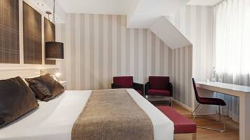 Una habitación de hotel moderna con una cama grande, un escritorio y una silla.