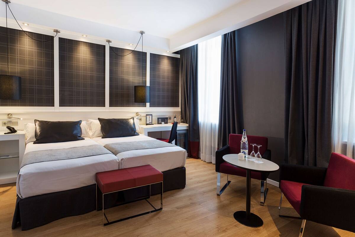 Ein modernes Hotelzimmer mit einem großen Bett, einem Schreibtisch und einem Essbereich.