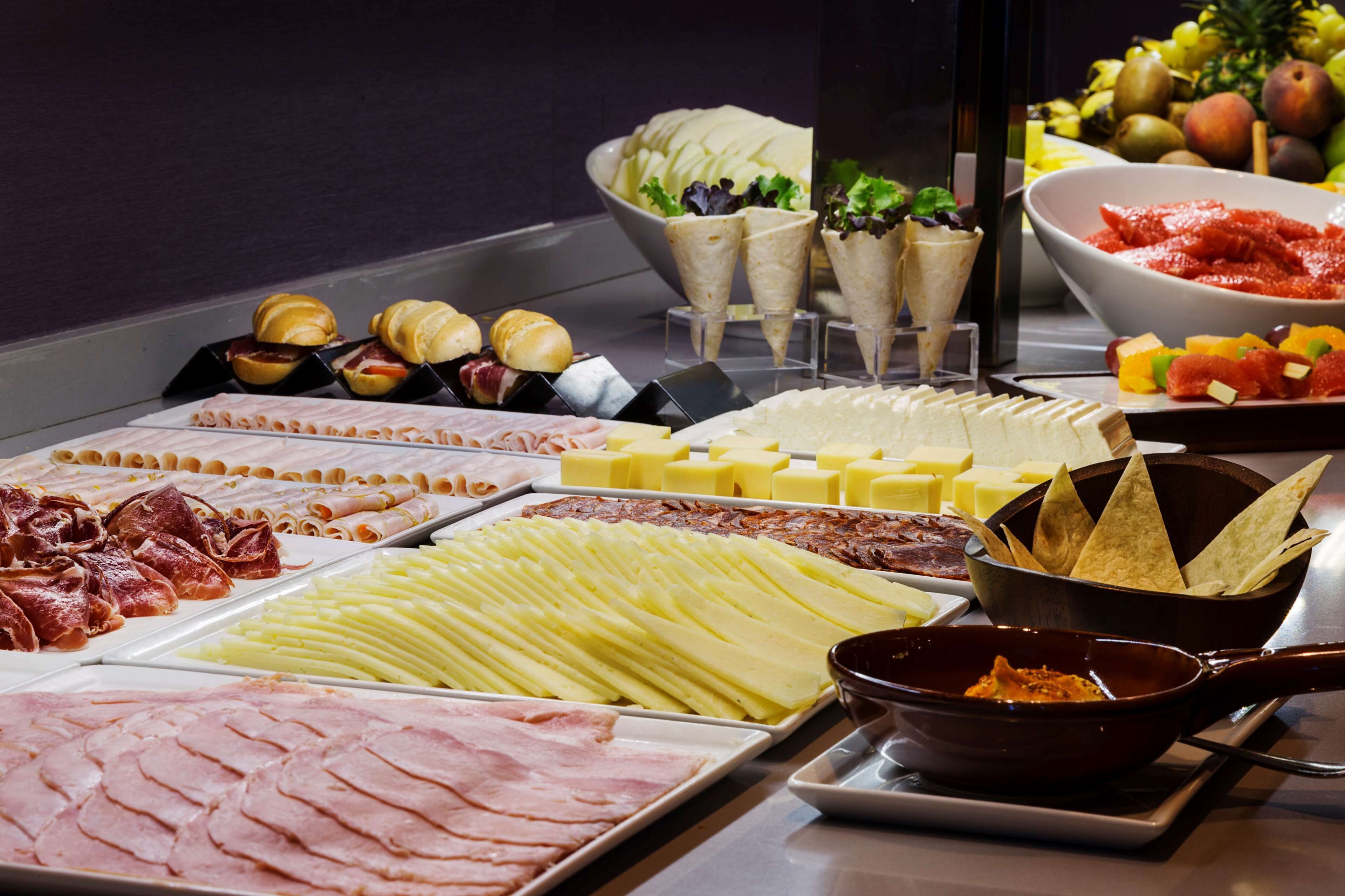 Ein Buffet mit verschiedenen Speisen, darunter Fleisch, Käse und Obst.