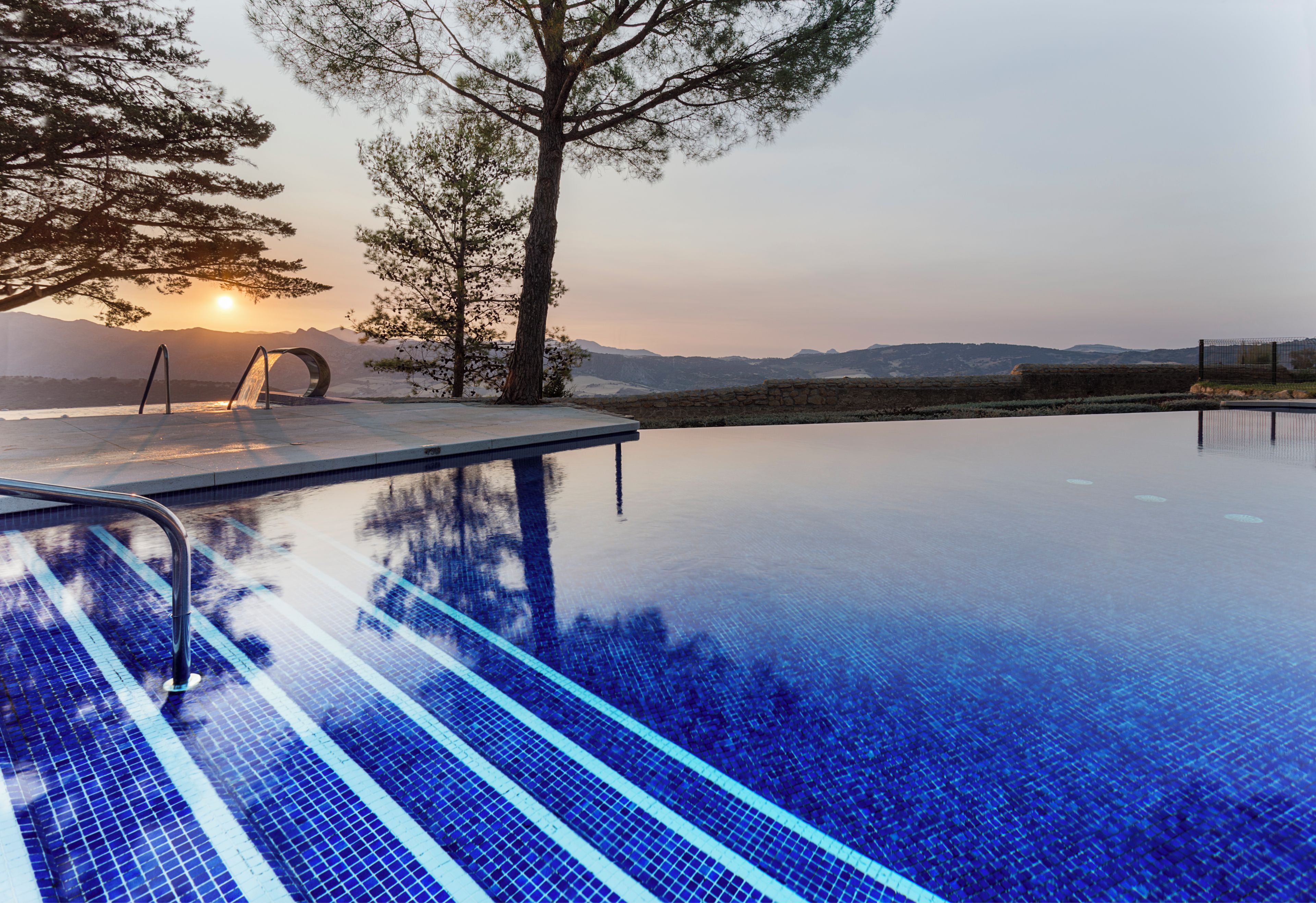 A clear swimming pool with a view of mountains in the background.