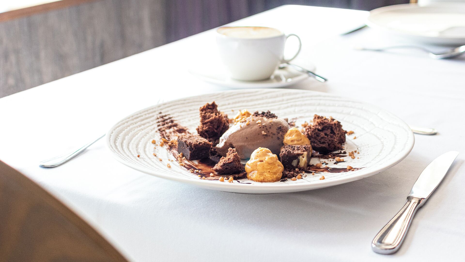 A dessert plate with brownies and ice cream on a white table.