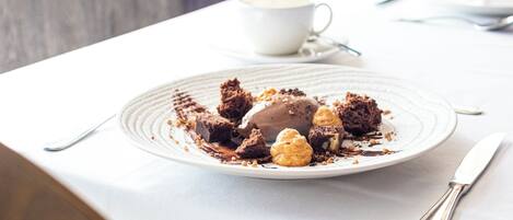 A dessert plate with brownies and ice cream on a white table.
