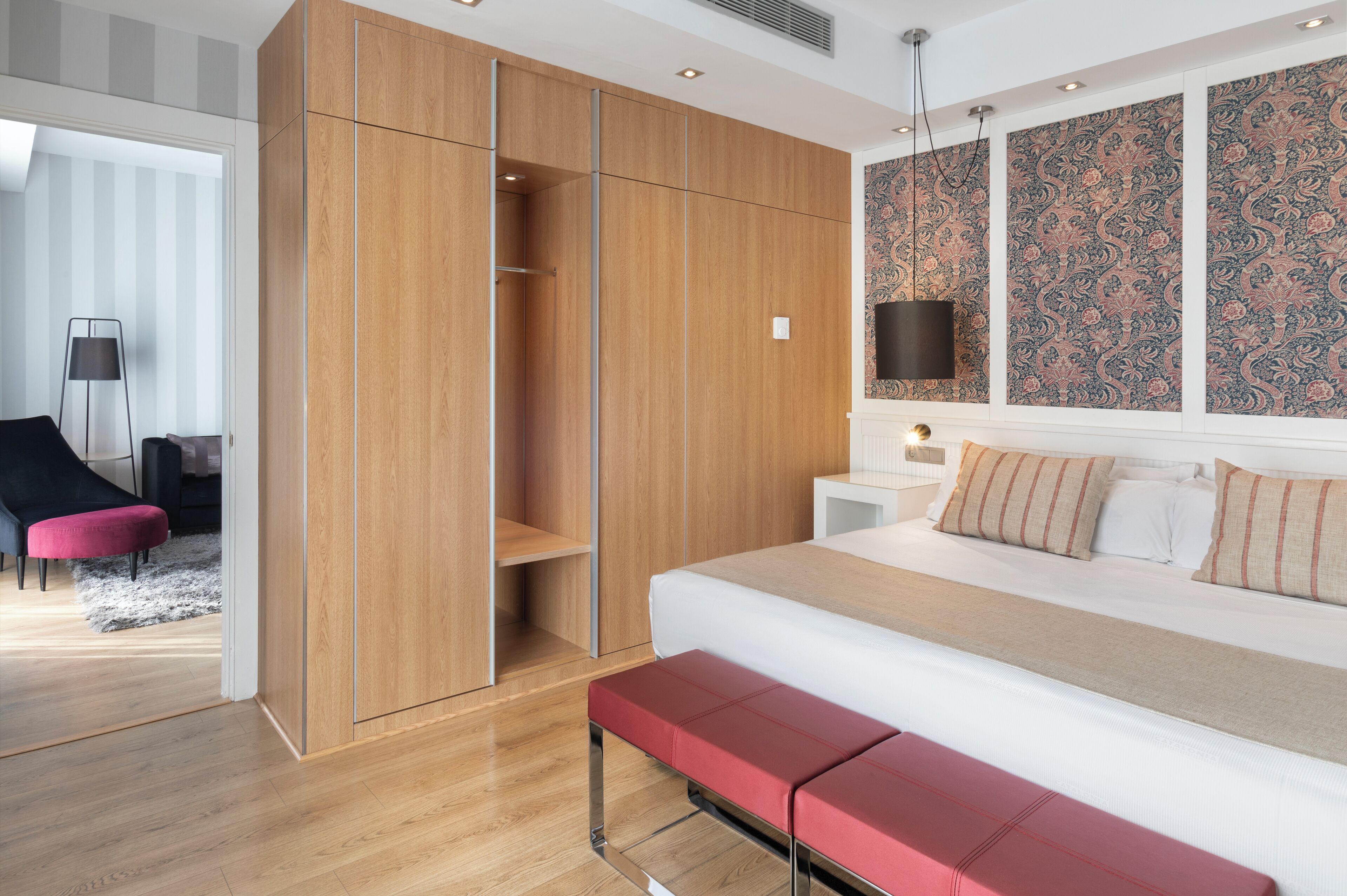 A modern bedroom with a large bed, a wooden wardrobe, and a patterned wall.