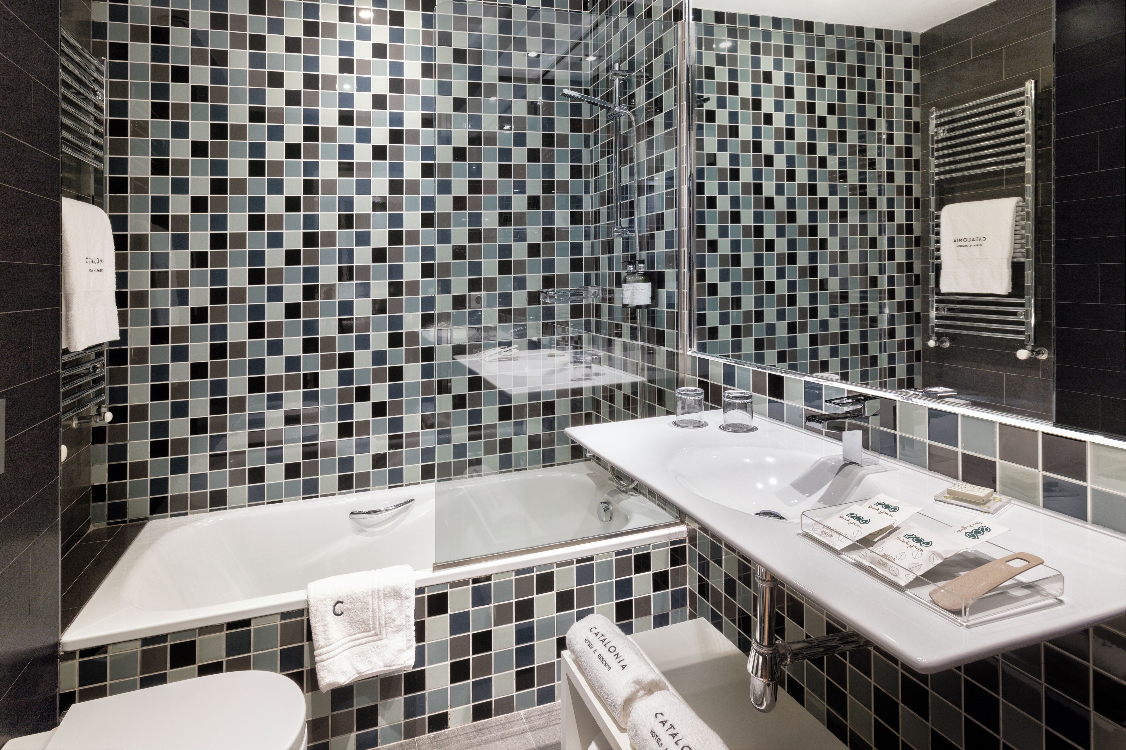 Un baño moderno con ducha envuelta en vidrio, una bañera blanca y un tocador con artículos de aseo.