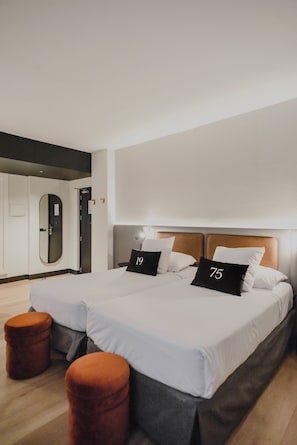 A modern hotel room with a large bed, two side tables, a mirror, and a door.