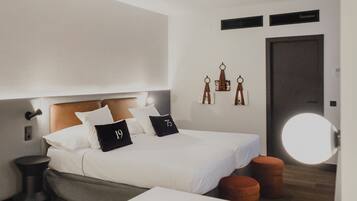 Una habitación de hotel moderna con cama, mesita de noche y un espejo redondo.