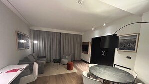 Un salon moderne comprenant un canapé, une table à manger avec des chaises, une petite table basse et un téléviseur fixé au mur.