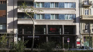 Un immeuble à plusieurs étages doté de balcons, d’une entrée pour le stationnement et d’une enseigne indiquant « dmh ».