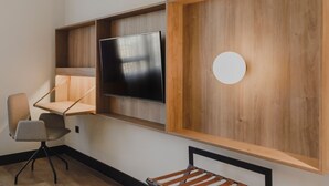 Une chambre moderne avec un plancher en bois, un téléviseur fixé au mur et un bureau avec une chaise.
