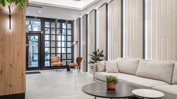 A modern lobby with a sofa, two chairs, a coffee table, and a wooden accent wall. - Hotel Don Jaime 54 (Zaragoza)
