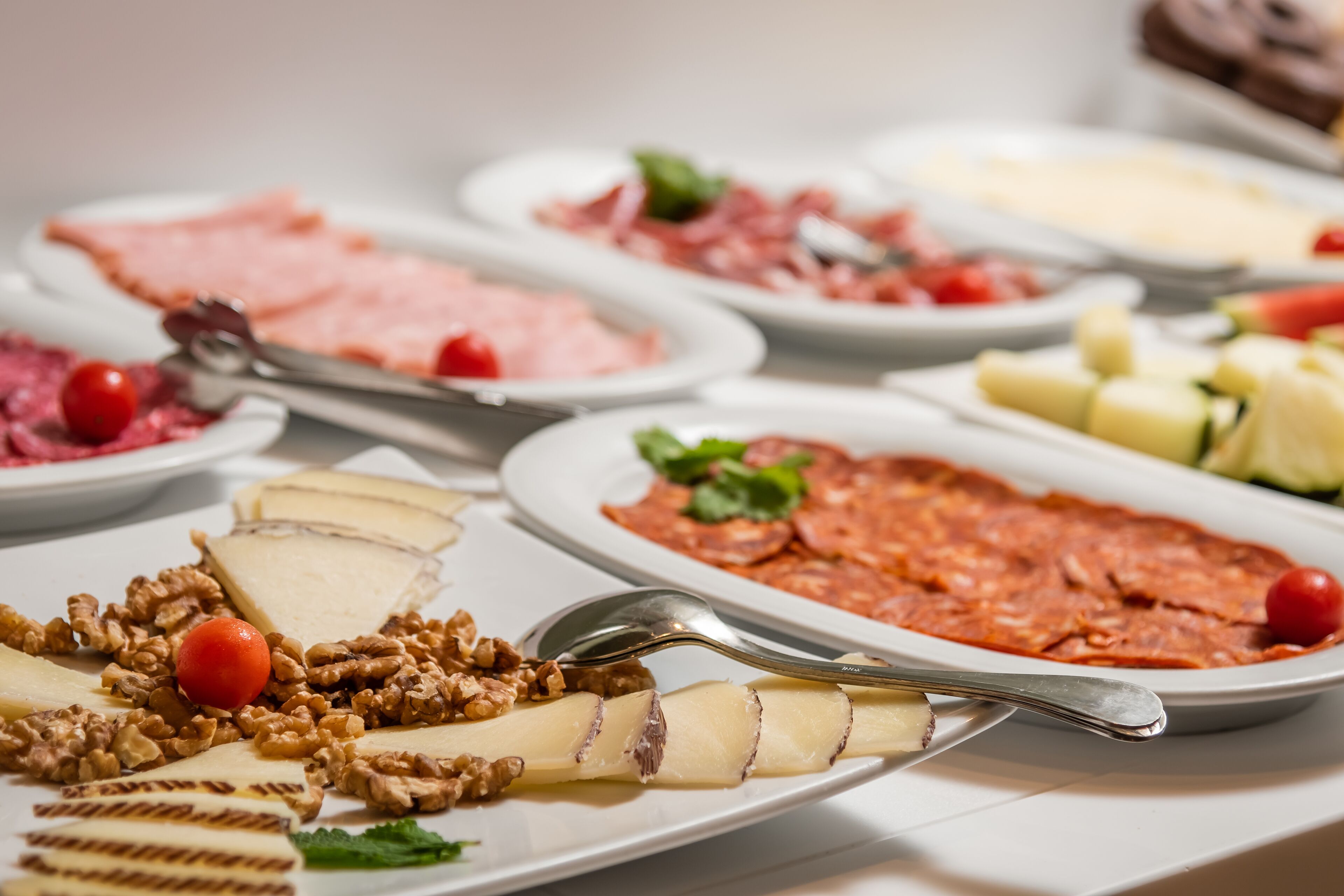 A buffet with various food items including meats, cheeses, and fruits.