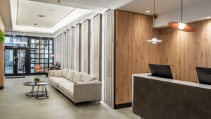 A modern reception area with a sofa, a round table, and a reception desk. - Hotel Don Jaime 54 (Zaragoza)