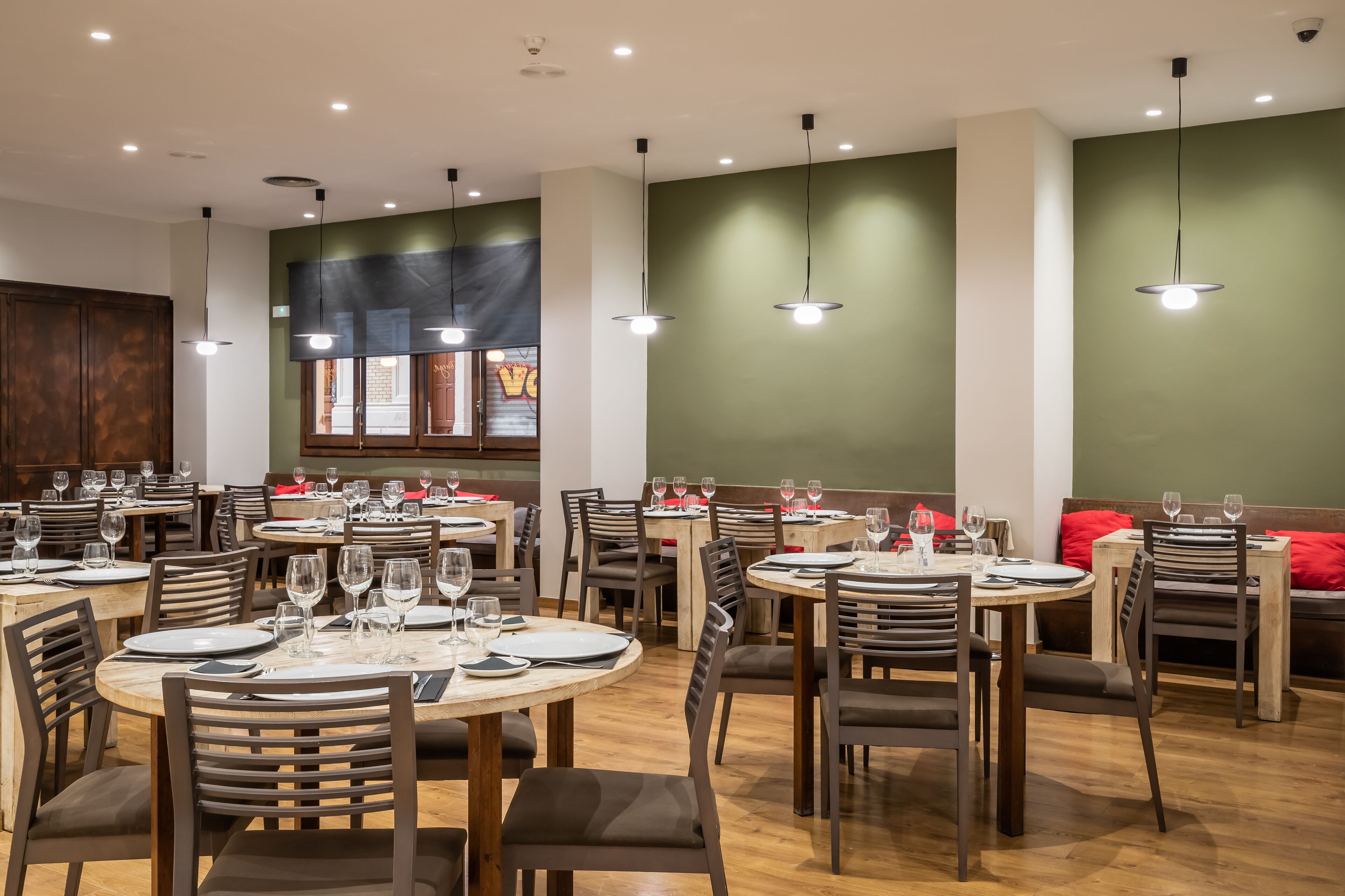 Un restaurante con mesas redondas, sillas y lámparas colgantes.