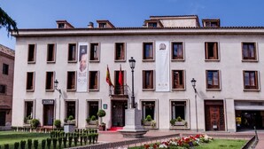 Un edificio de varios pisos con un patio central, un asta de bandera y una estatua.