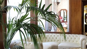 Un sofá blanco con capitoné en una habitación con ventanas amplias y una planta en maceta.