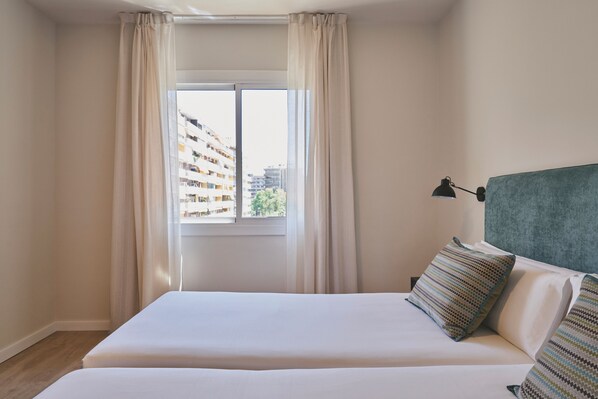 A hotel room with a large window, a bed with two pillows, and a headboard.