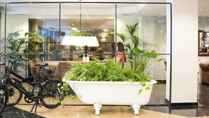 Un vestíbulo moderno con una bañera grande llena de plantas, una bicicleta y un comedor al fondo.
