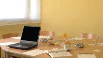 A dining area with a laptop on a table, a book, and a glass of orange juice.