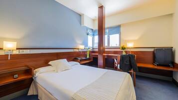 Una habitación de hotel con una cama grande, mesitas de noche, un escritorio y una silla.