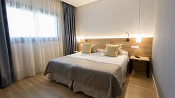 Una habitación de hotel moderna con una cama grande, dos mesitas de noche y una mesilla.