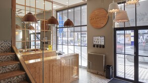 A reception area with a wooden counter, glass doors, and a view of the street. - Hotel Avenida (Pamplona)
