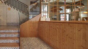 A staircase with patterned tiles leading to a wooden wall with a glass partition. - Hotel Avenida (Pamplona)