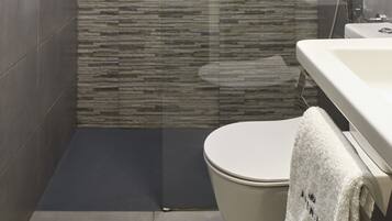 A modern bathroom with a glass-enclosed shower, a toilet, and a sink.