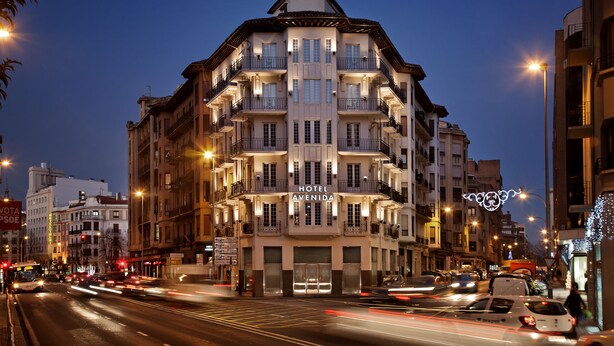 A multi-story hotel with balconies, large windows, and a sign indicating it is a hotel. - Hotel Avenida (Pamplona)