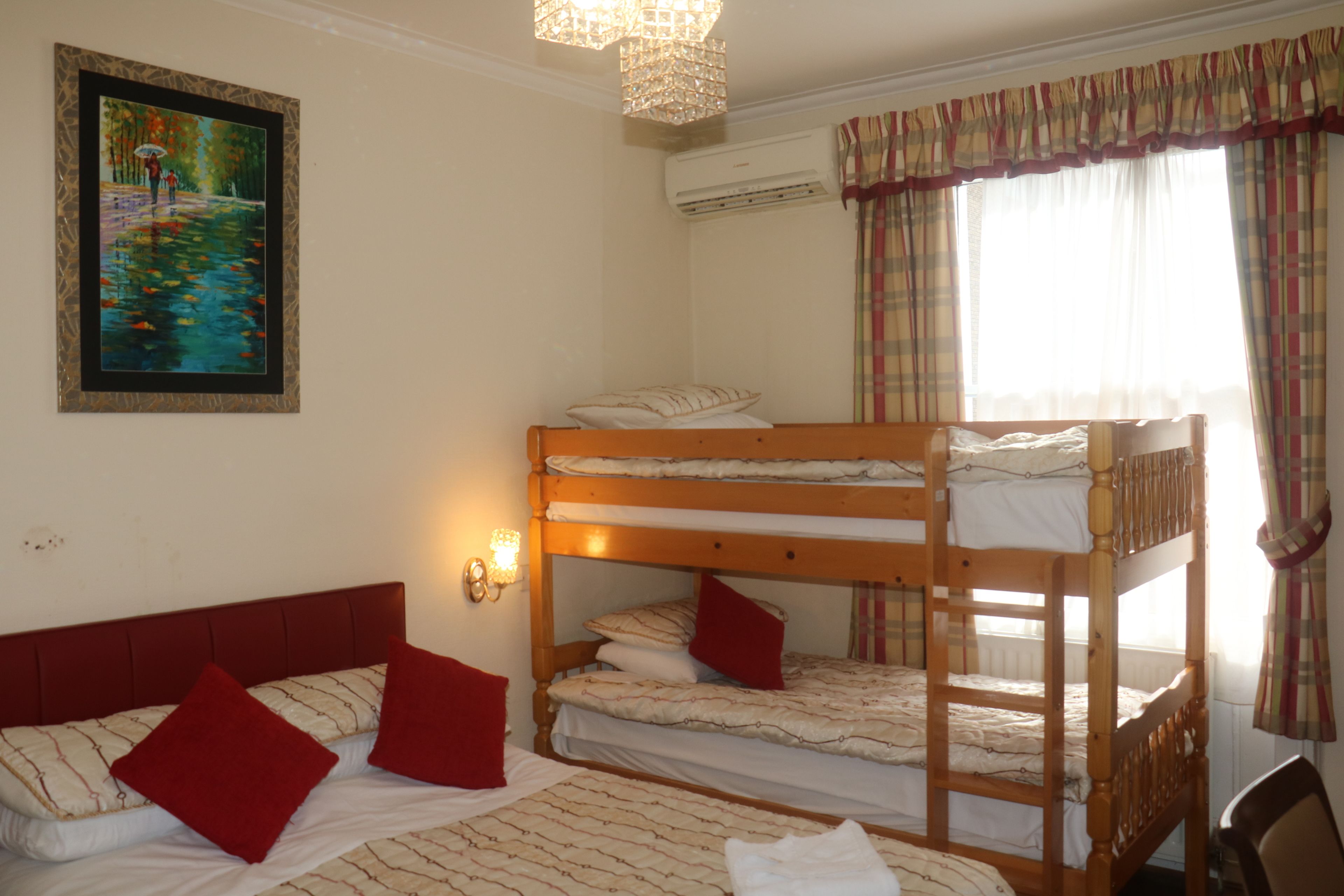 A room with bunk beds, a painting on the wall, and a window with curtains.