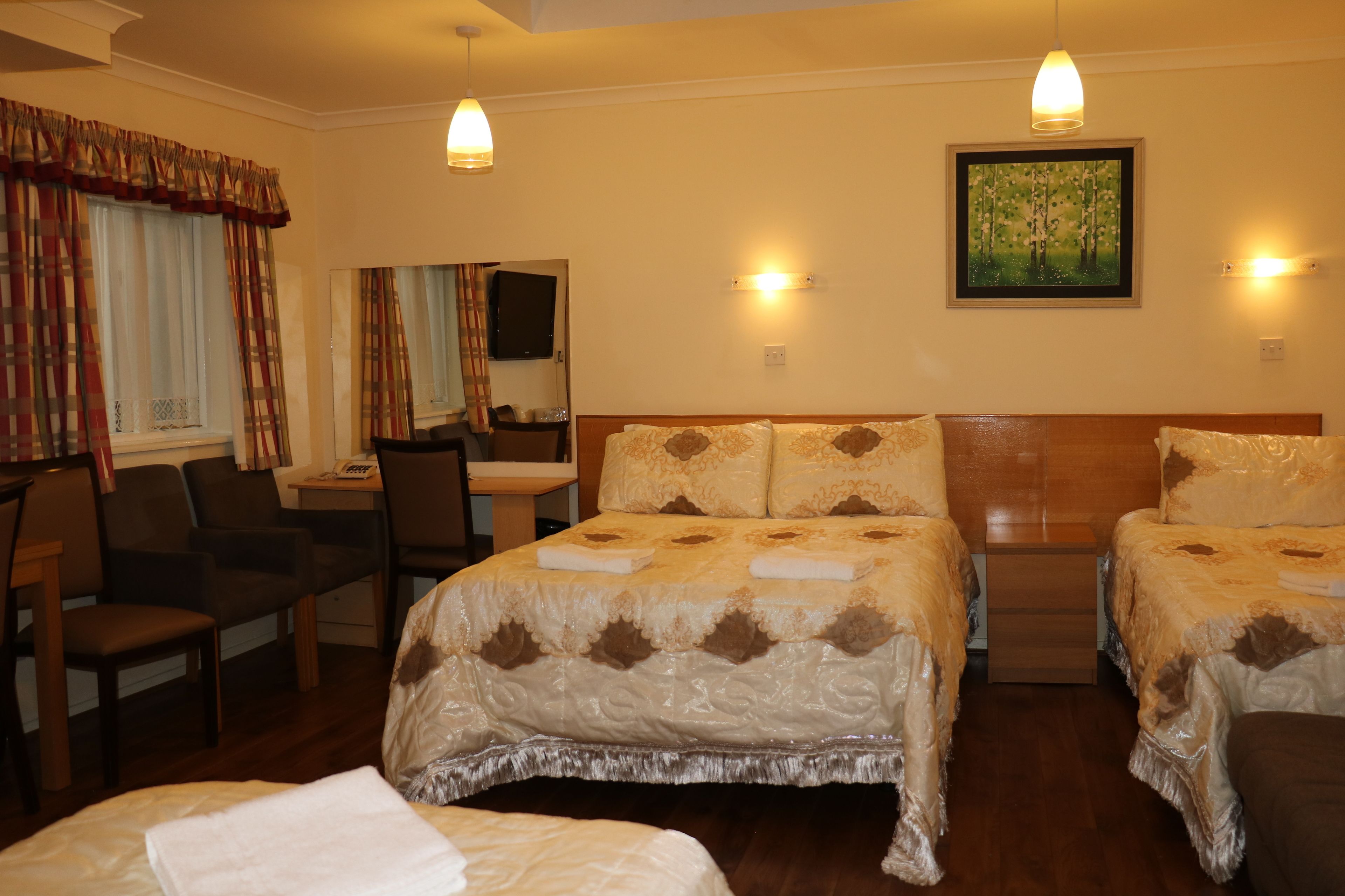 A hotel room with two beds, a desk, a chair, and a television.