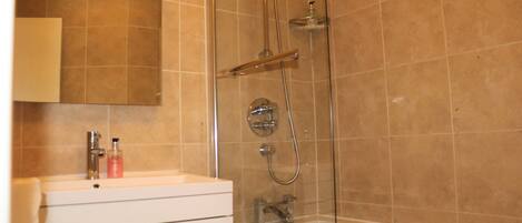 A bathroom with a glass-enclosed shower, a white vanity with a mirror, and a bathtub.