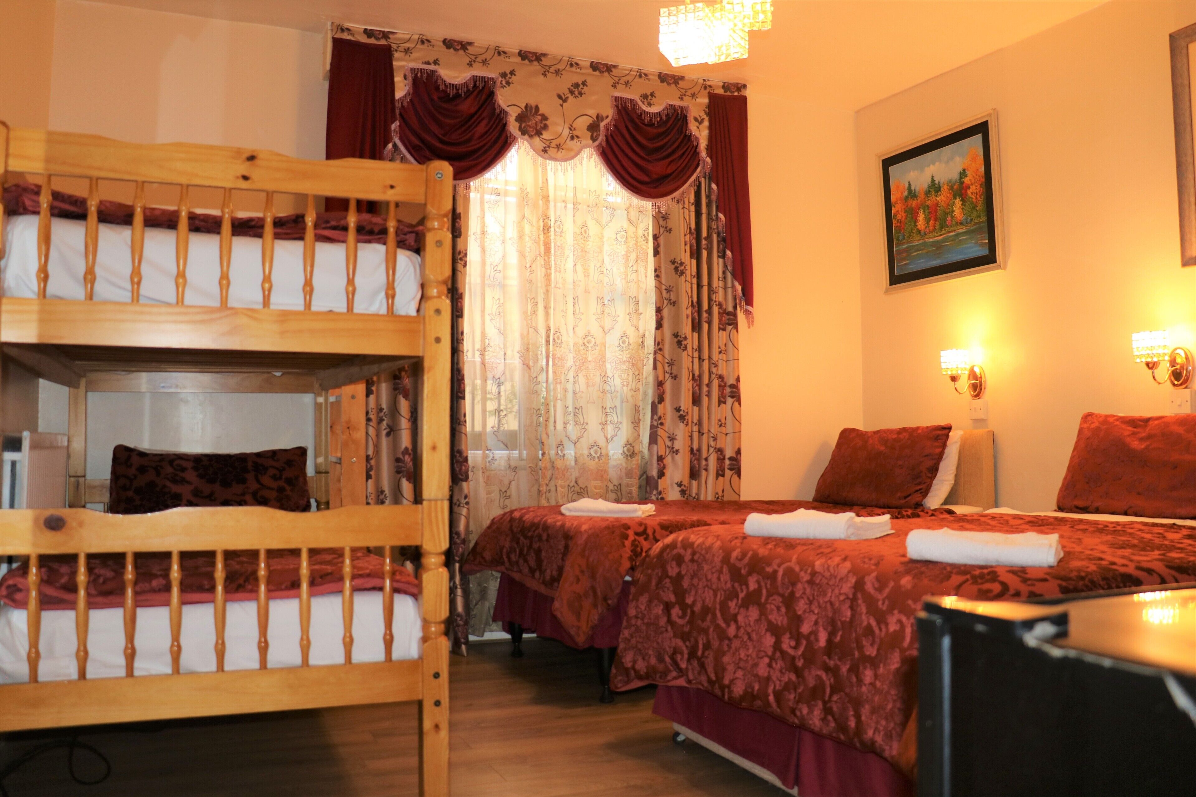 A room with two beds, a wooden bunk bed, and a desk.