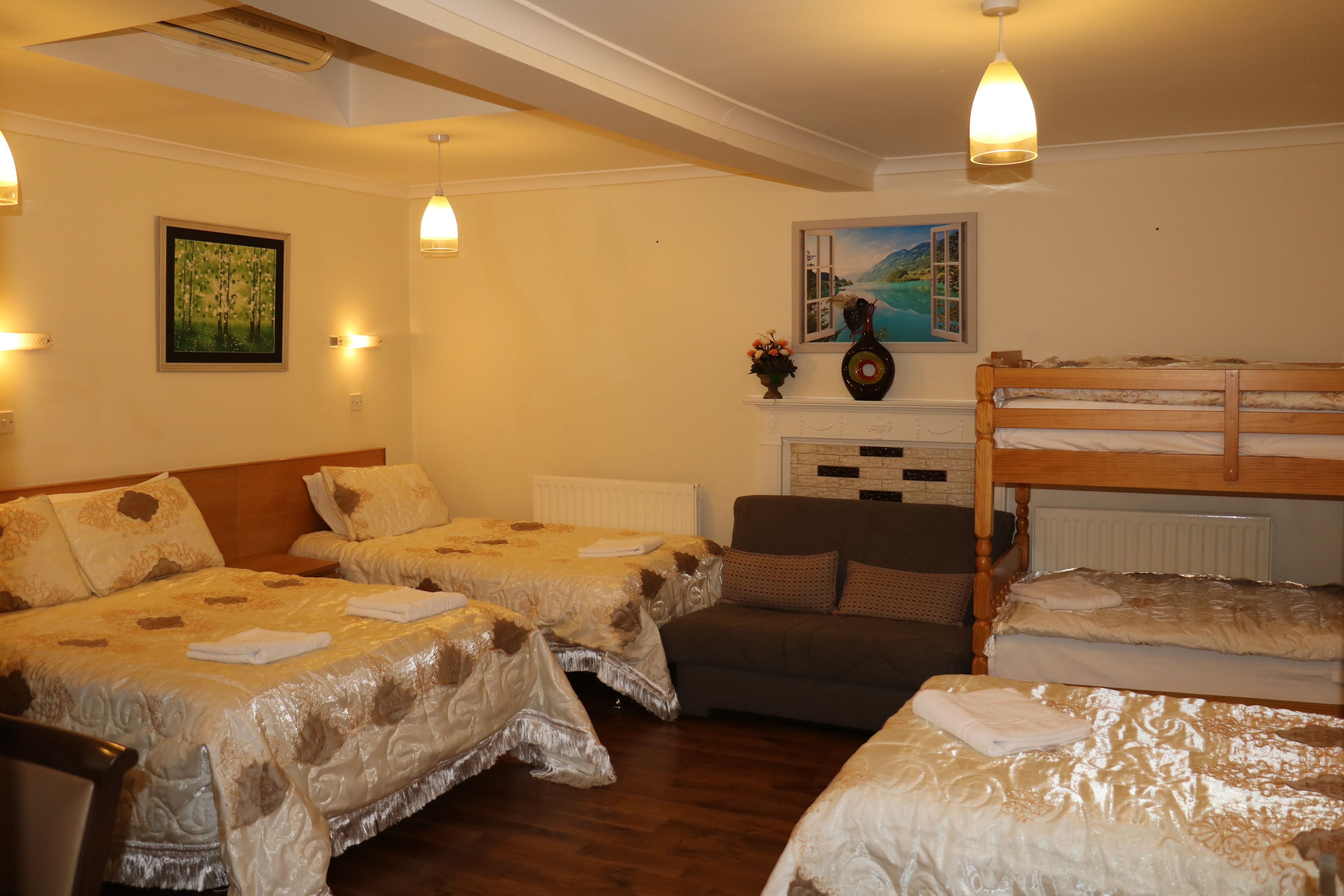 Una camera d'albergo con due letti singoli, un divano e un letto a castello.