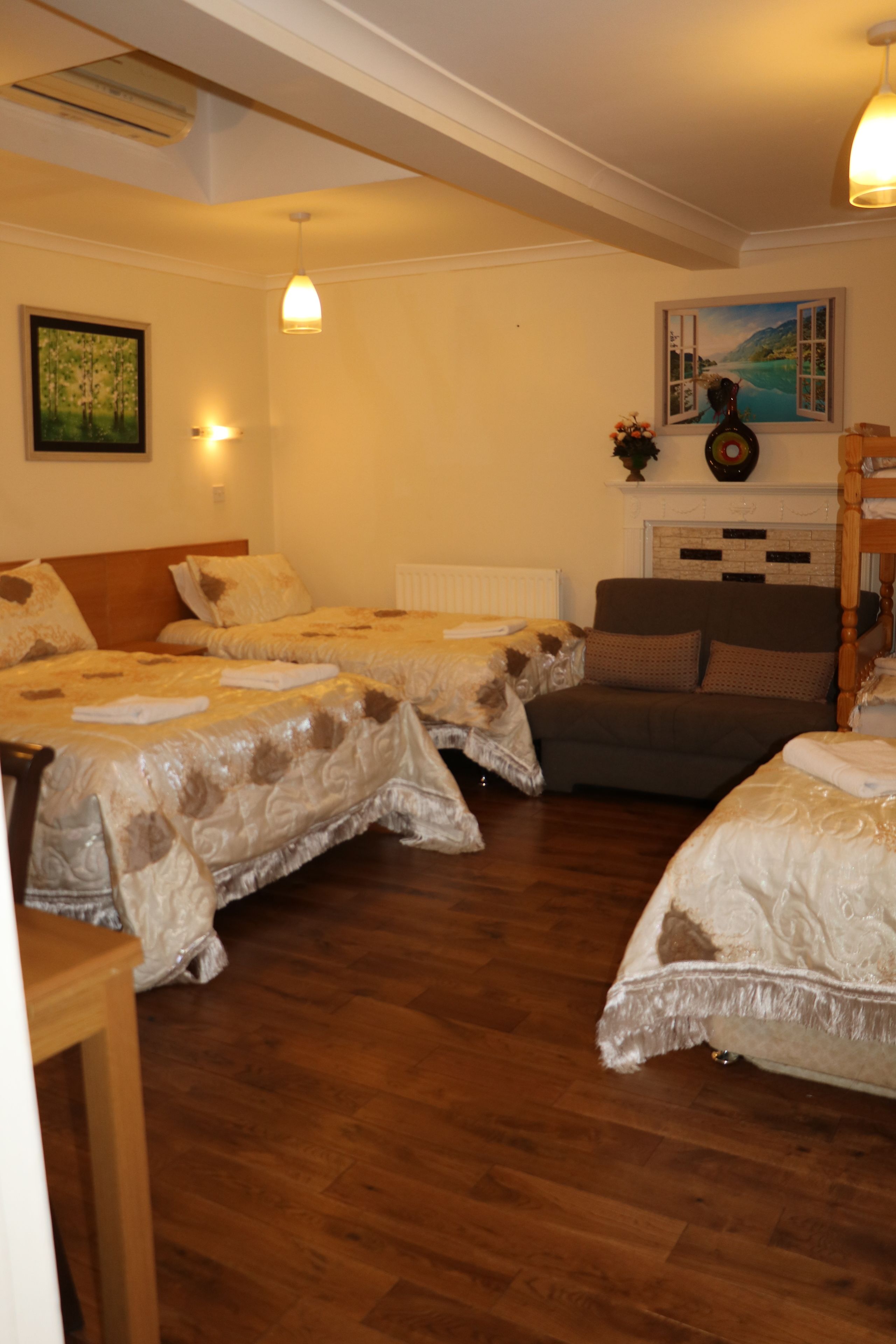 Ett hotellrum med två sängar, en soffa, en öppen spis och en tavla på väggen.