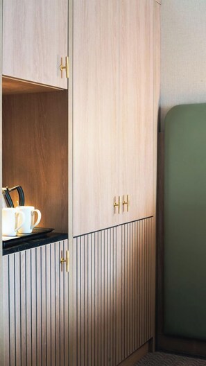 A kitchenette with wooden cabinets, a countertop, and a green upholstered chair. - Menlo Park Hotel (Galway)