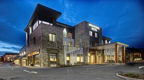 A modern hotel with a stone facade, large windows, and a well-lit entrance. - Menlo Park Hotel (Galway)