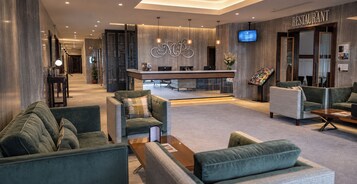 A modern lobby with seating areas, a reception desk, and a restaurant sign.