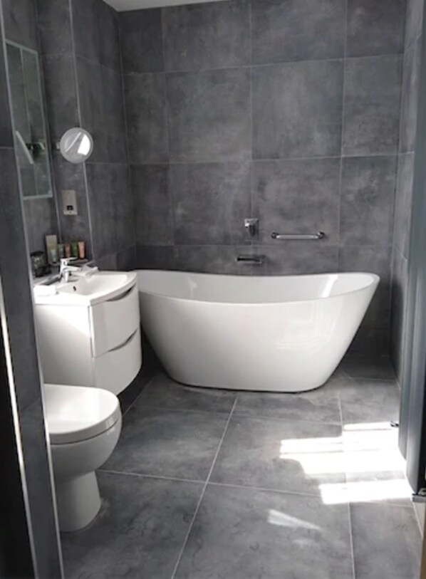 Un baño moderno con una bañera independiente, inodoro y tocador.