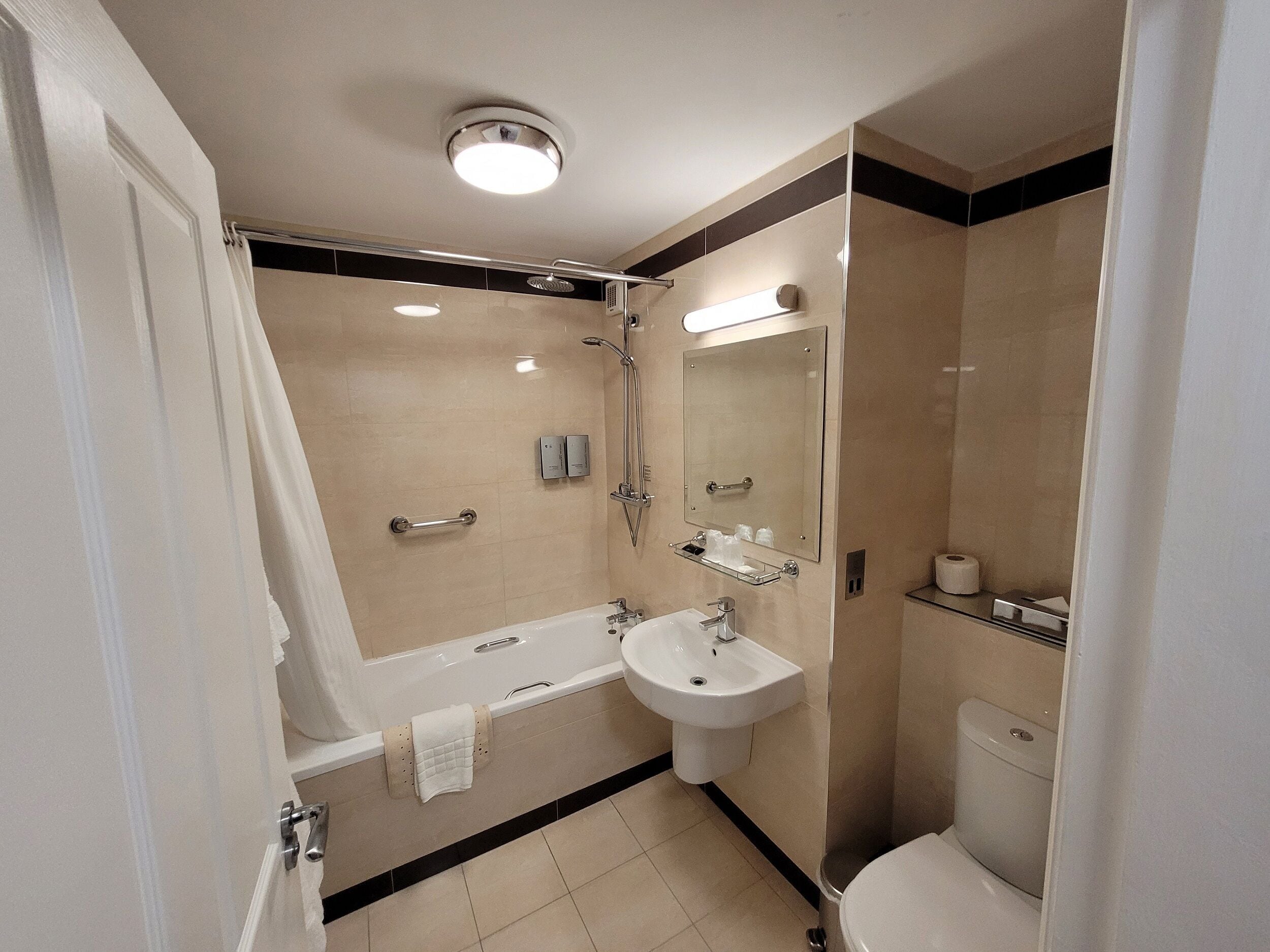 Une salle de bain moderne avec une baignoire, un lavabo, des toilettes et un grand miroir.