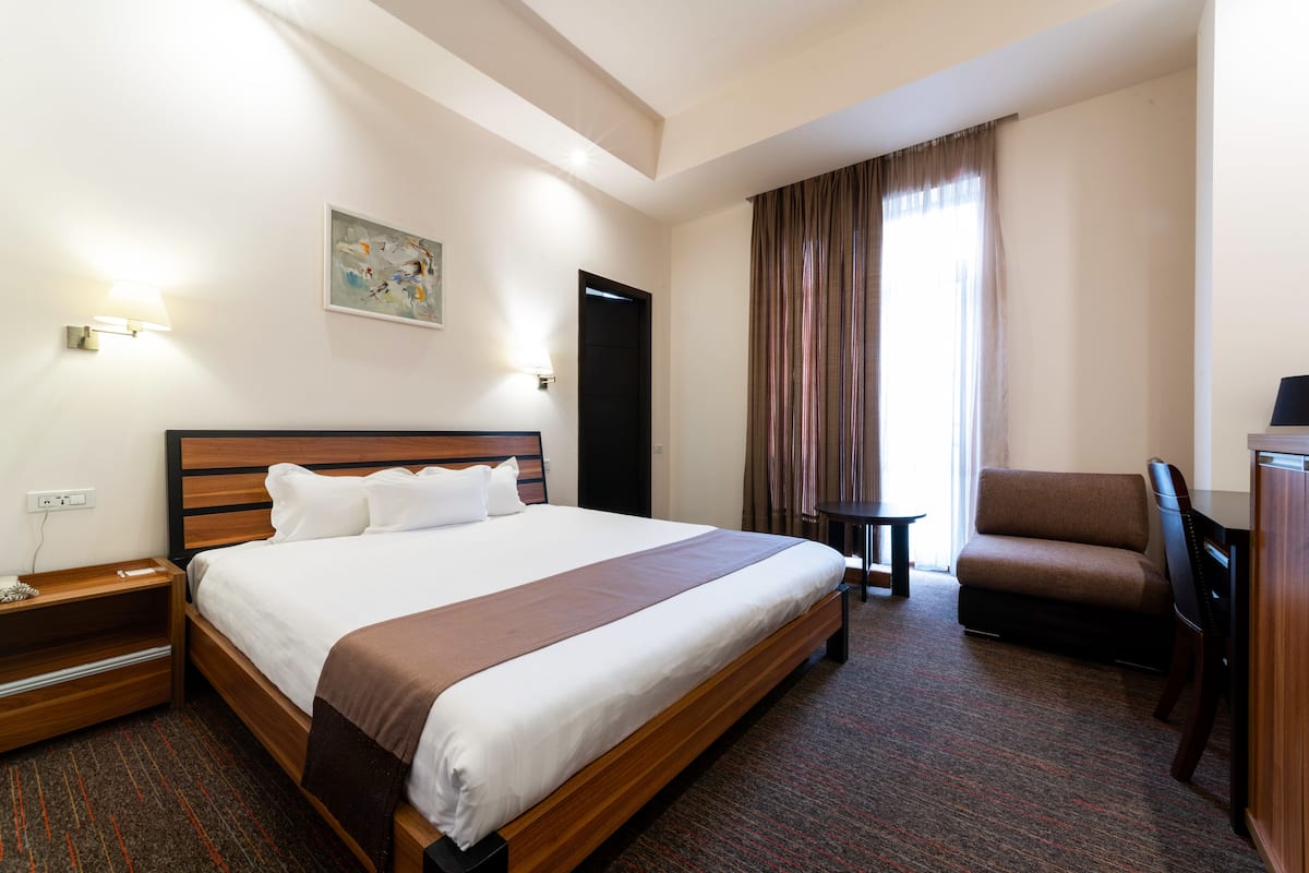 Une chambre d’hôtel avec un grand lit, un bureau, une chaise et un téléviseur.
