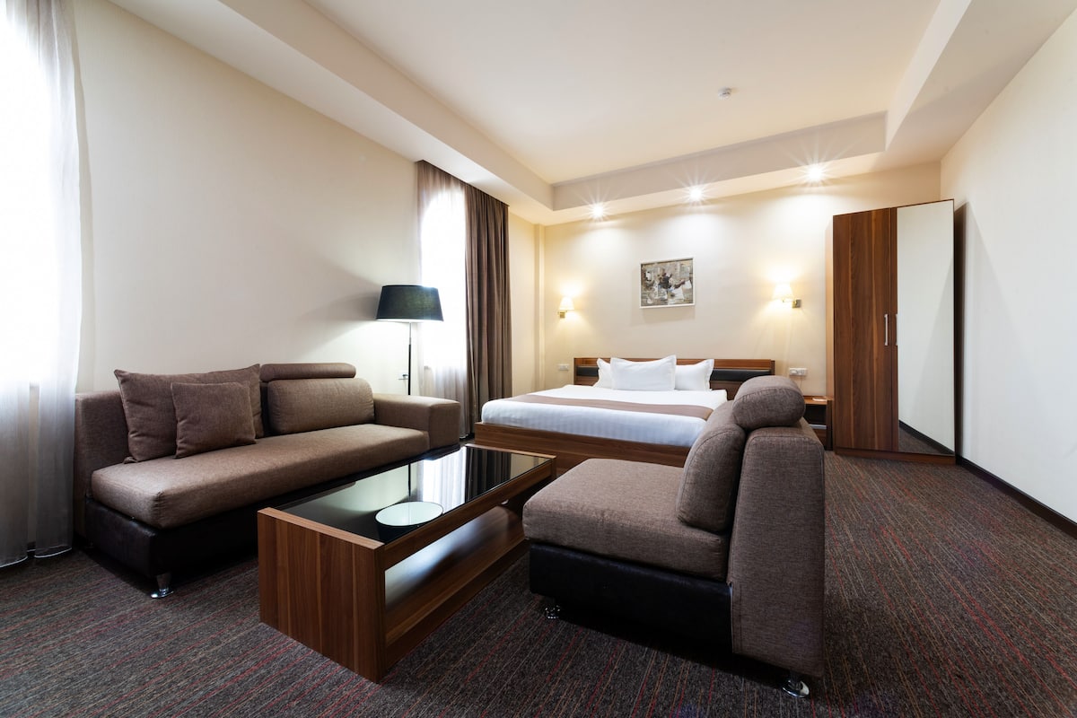 Une chambre d’hôtel équipée d’un canapé, d’un lit, d’un bureau et d’une armoire.