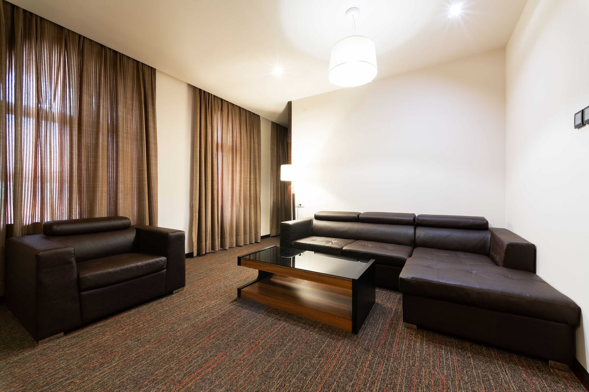 Un salon moderne avec un canapé d’angle, un petit fauteuil et une table basse avec un plateau en verre.