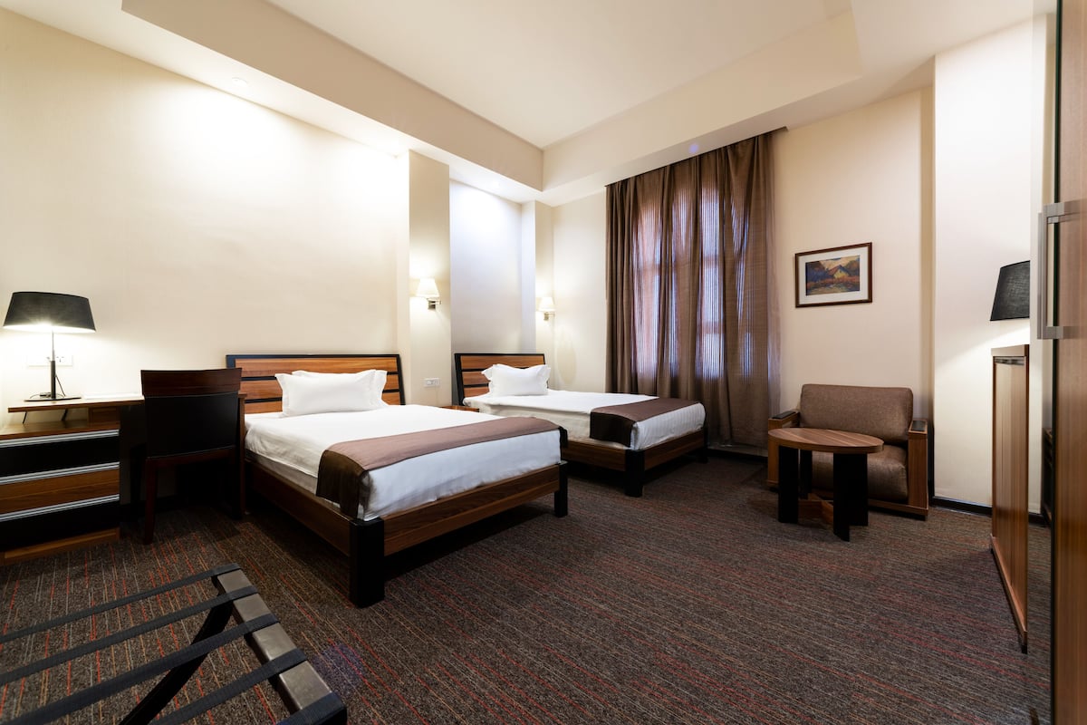 Une chambre d’hôtel avec deux lits, un bureau, une chaise et une petite table.
