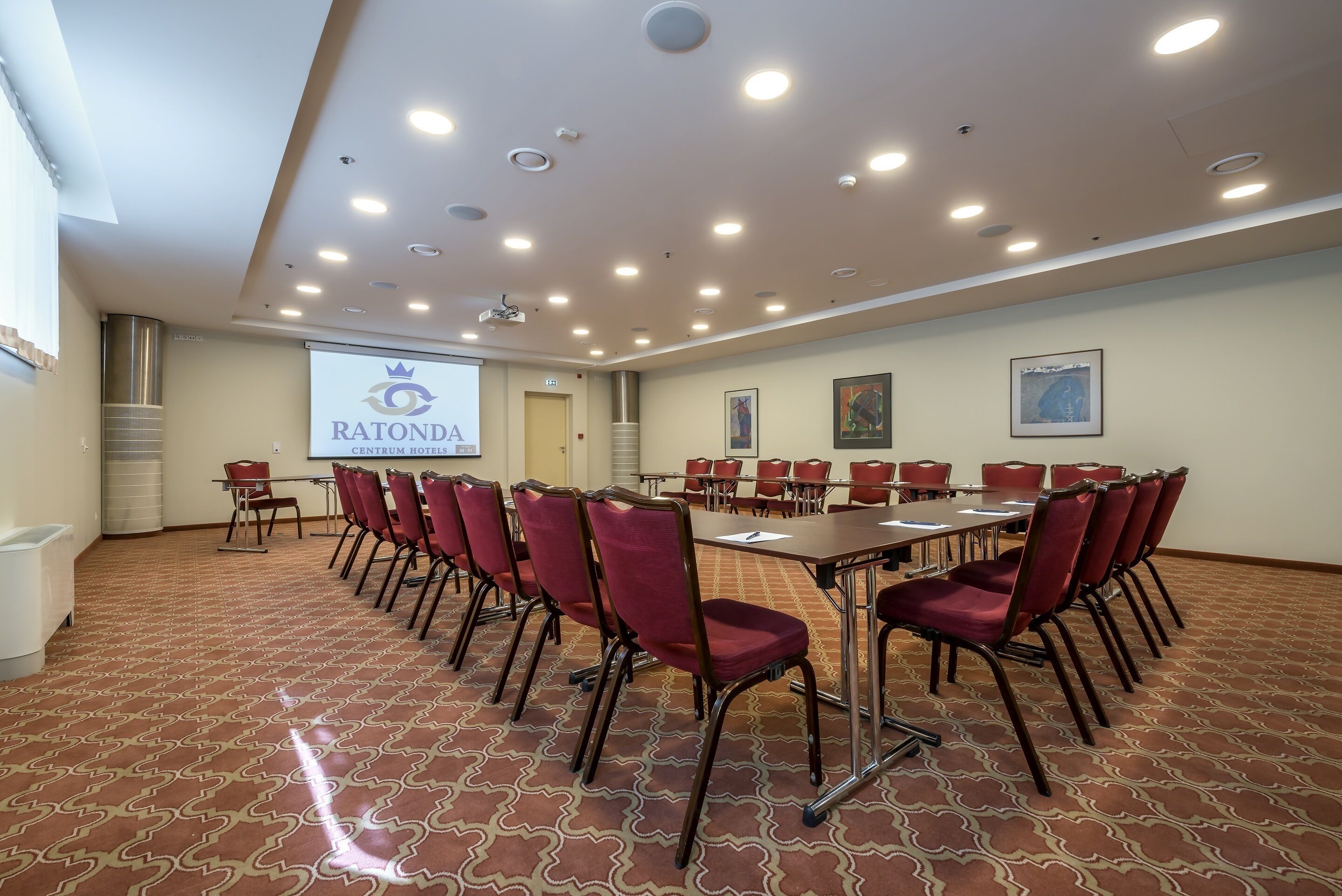 Uma sala de conferências com uma tela grande exibindo 