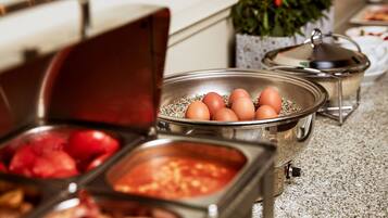 A buffet setup with various food items in metal containers, including eggs and what appears to be a red fruit dish.