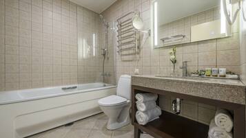 A modern bathroom with a bathtub, toilet, and a vanity with towels.