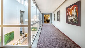 A corridor with patterned carpet, large windows, and artwork on the walls. - Ratonda Centrum Hotels (Vilnius)